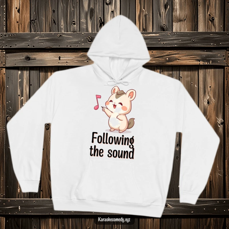 Funny Hoodie depicting a small animal joyfully pointing at a bouncing musical note, radiating a sense of playful discovery.
